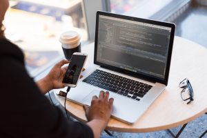 person looking at phone and macbook