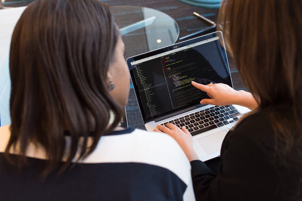 women analysing code on laptop