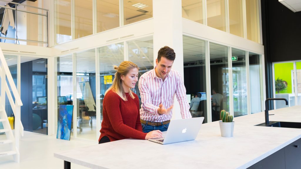 young man and woman talking in front of laptop