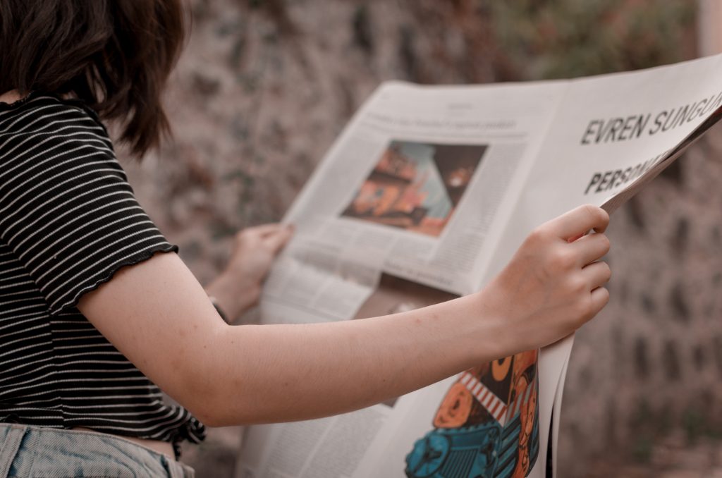 person reading newspaper with text and illustrations