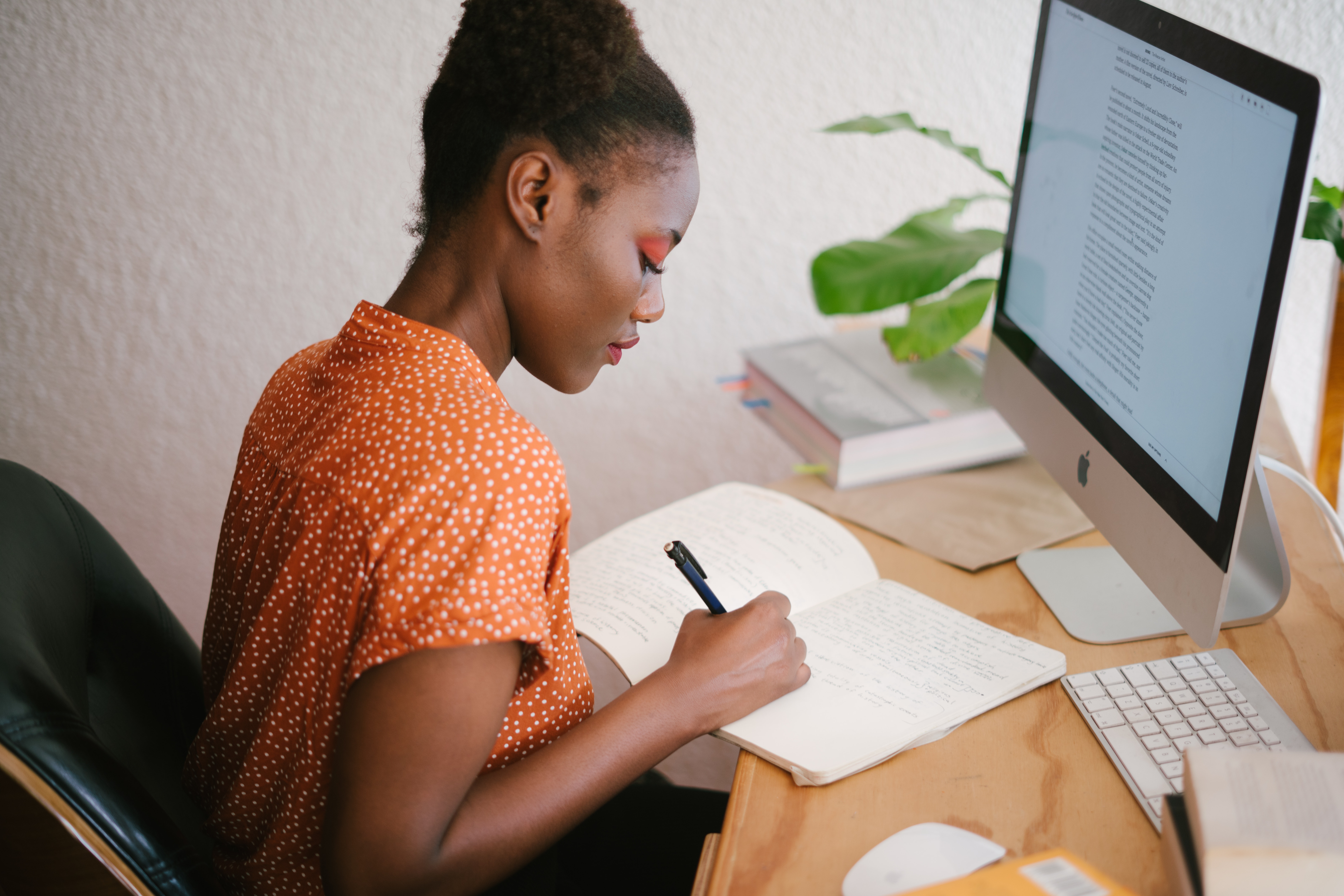 woman from dedicated team writing in notebook and working remotely