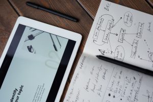 ipad notebook and pen on wooden table for data gathering