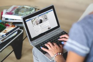 person with laptop open to facebook page